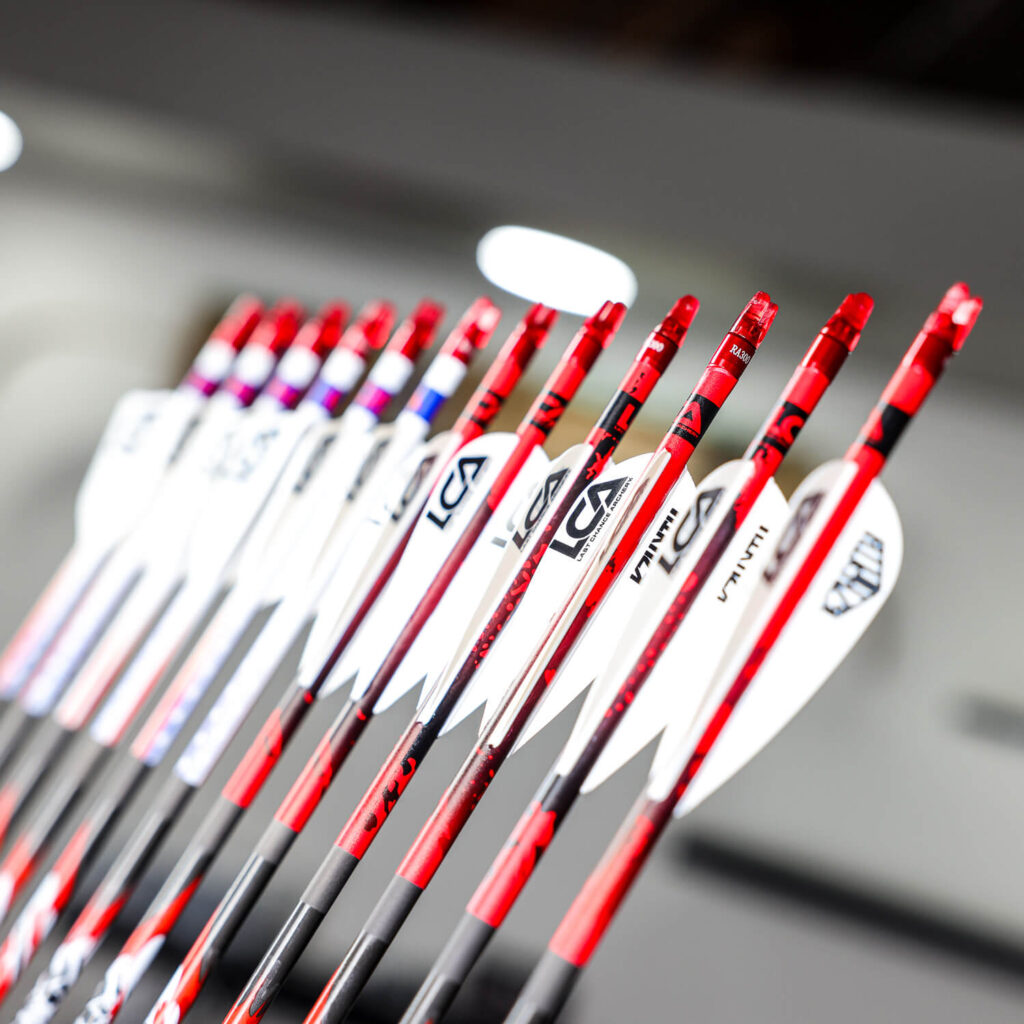 nicely fletched custom arrows for archery shown in white vanes with red nocks and carbon shafts